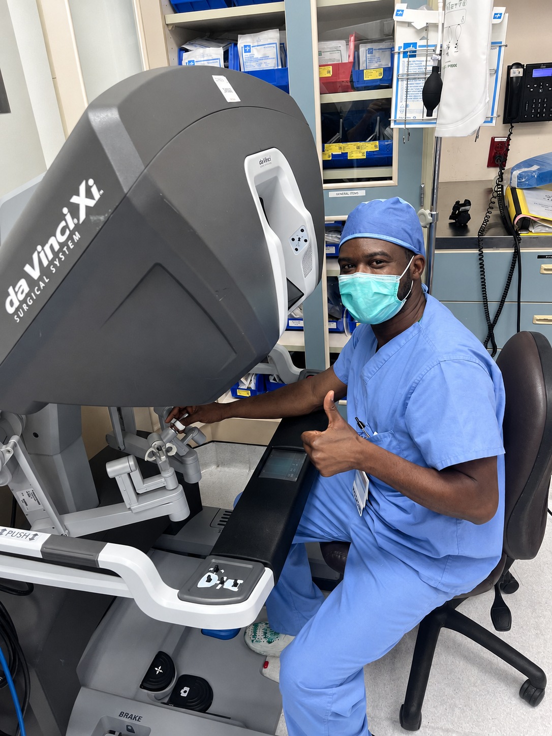 Dr. Michael Clerveus in surgical scrubs beside a da Vinci Xi surgeon console